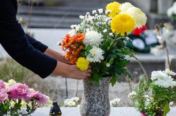 personne posant fleurs sur cimetiere