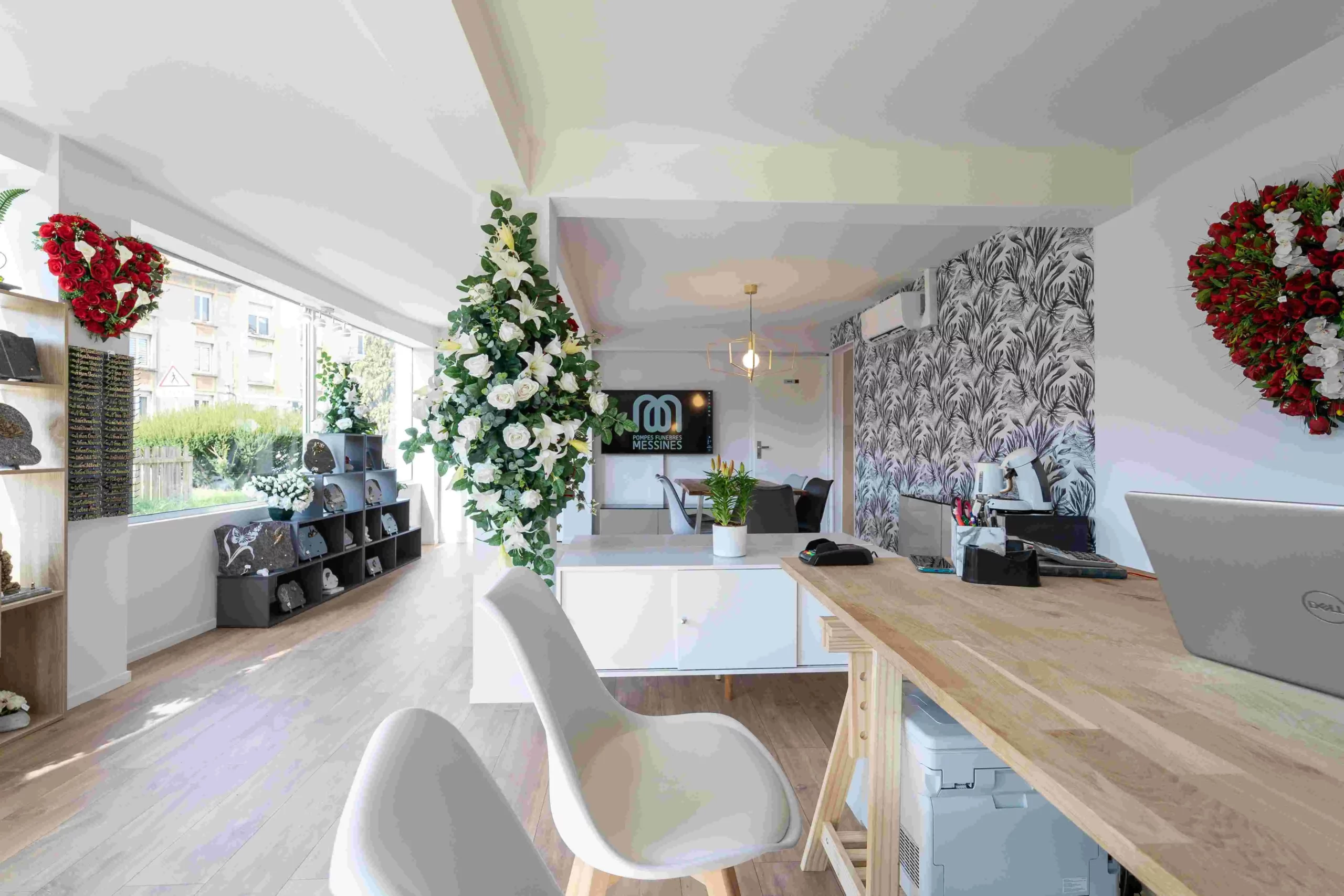 Intérieur de l'agence Pompes Funèbres Messines avec bureau d'accueil et compositions florales